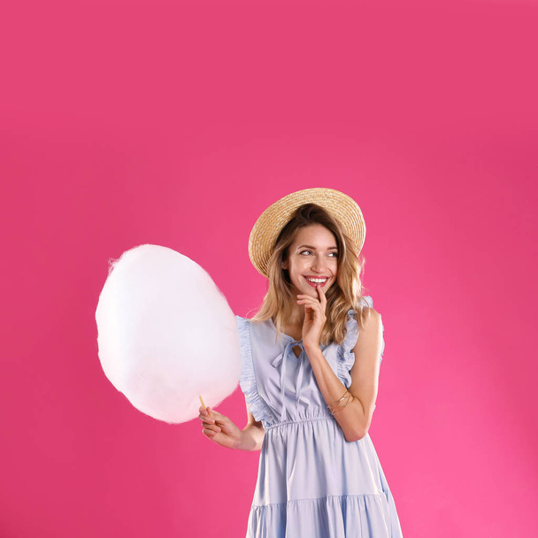 Happy young woman with cotton candy on pink background - Foto, Bild
