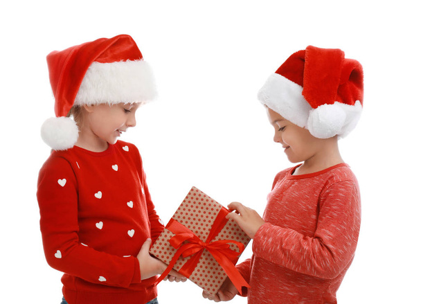 Cute little children wearing Santa hats with Christmas gift on white background - Fotó, kép