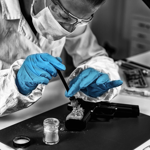 Forensic technician examining weapon, looking for fingerprints. Forensic Science Laboratory. - Photo, image