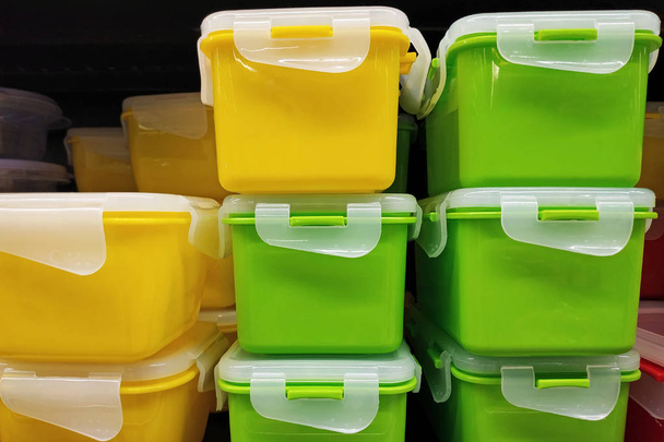 Recipientes de plástico verde y amarillo con tapa, de cerca. Envases universales. Cajas de plástico brillante con tapas para almacenar alimentos y verduras. Utensilios de cocina modernos en la tienda
. - Foto, imagen