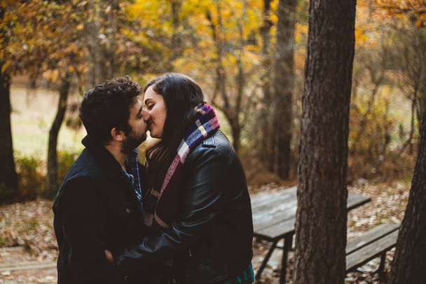 Couple in love kissing on autumn in the autumnal forest, enjoying a beautiful day. Couple kissing in the colorful orange and yellow park. - 写真・画像
