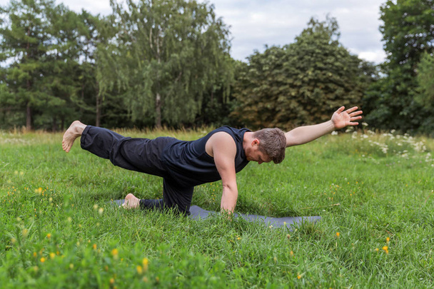 Inspired man doing yoga asanas in city park. Fitness outdoors and life balance concept. - Fotografie, Obrázek