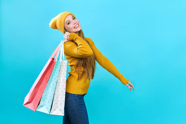 Fashionista girl with bags. Young happy woman with purchases. Joyful beauty was on sale, on a blue background. - Fotografie, Obrázek
