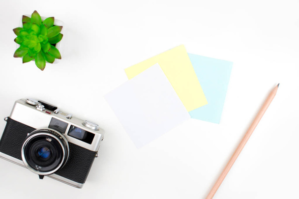 Note pad, film camera, pencils and plant pots on a white desk. T - Foto, Bild
