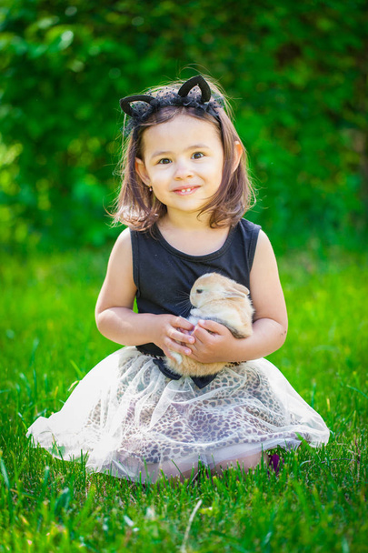 Portrait of a cute little girl with a rabbit in her arms. - Fotografie, Obrázek