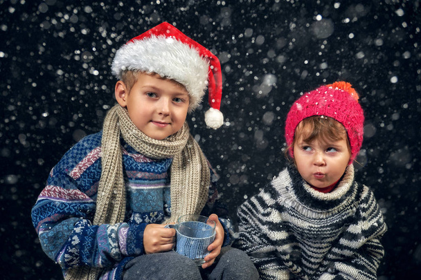 Siyah arka planda sıcak şapkalı çocukların portresi. Mutlu kardeşlerim Noel arifesinde - Fotoğraf, Görsel