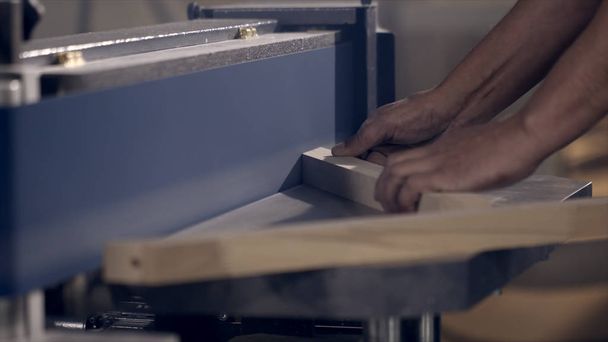 Lähikuva mies jauhaa puutuotteita teollisuuden koneella. Toimintaa. Carpenter kiillottaa puinen tuote nauha valmistus kone
 - Valokuva, kuva