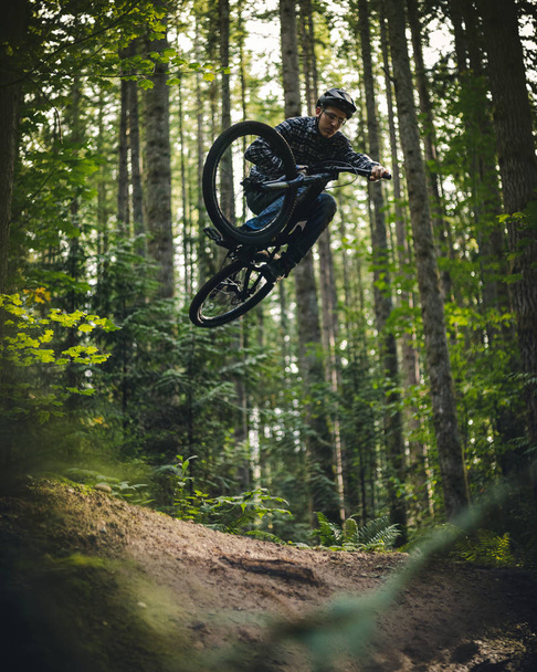 Artistieke Mountain Bike Jump Air omlijst door Forest Foliage - Foto, afbeelding