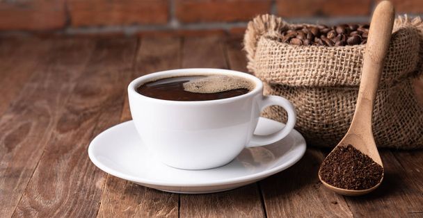 Coffee cup,coffee ground and coffee beans in burlap on wood tabl - Фото, зображення