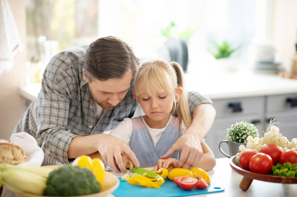 Bonita filha ajudando filha enquanto corta legumes
 - Foto, Imagem