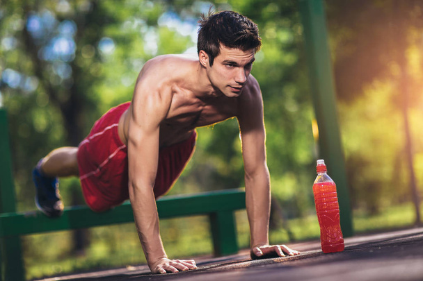 Picture of a young athletic man doing push ups outdoors. - Foto, immagini