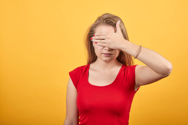 Jong blond meisje in rood t-shirt over geïsoleerde oranje achtergrond toont emoties - Foto, afbeelding