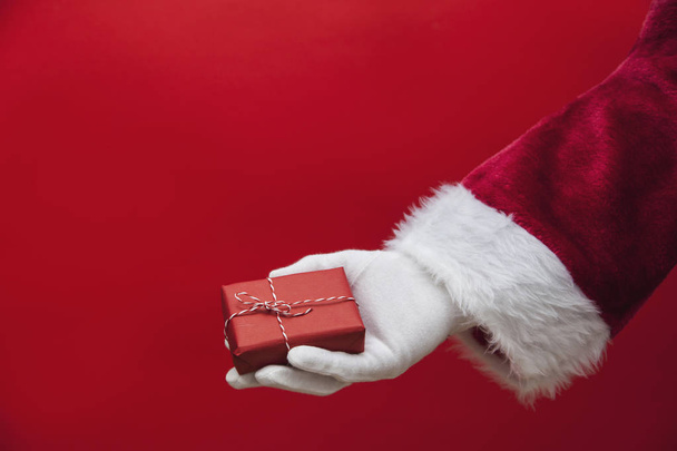 Santa Claus hand holding a Christmas present - Фото, изображение