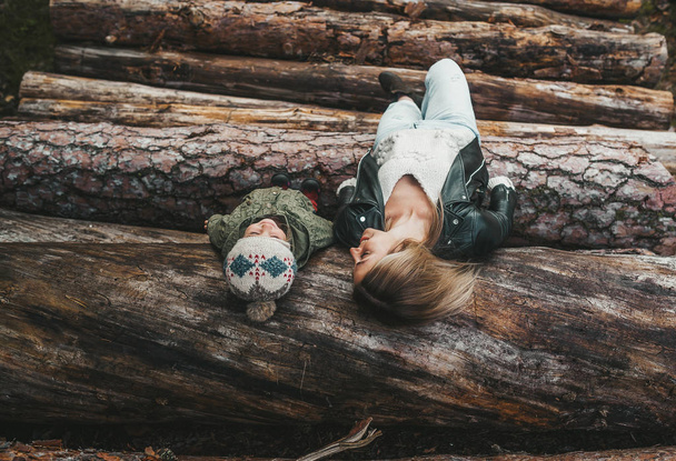 Retrato otoñal de la madre y la niña acostadas en una pila de troncos
. - Foto, Imagen