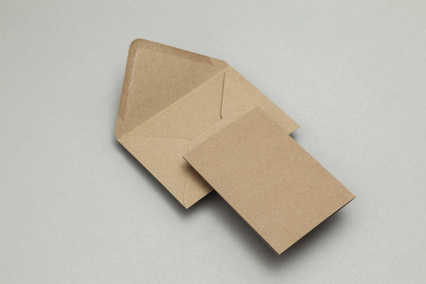 Blank brown kraft paper card and envelope on a grey background - Foto, afbeelding