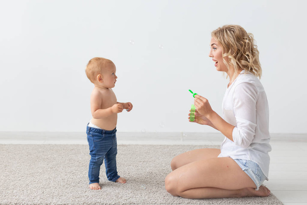 Concepto de familia e infancia - Retrato de la madre y el bebé jugando y sonriendo en casa
. - Foto, Imagen