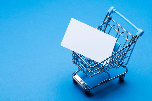 Shopping cart on a blue background with blank label - Foto, immagini