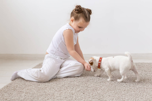 Pets and animal concept - Child girl playing with puppy Jack Russell Terrier - Foto, afbeelding