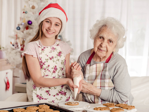 Grandmother with granddaughter decorate cookies - Foto, Bild