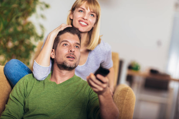 Young couple watching TV on a sofa at home - Foto, Bild