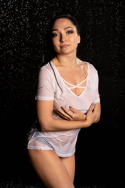 Beautiful girl in wet white t-shirt on black background - Foto, afbeelding