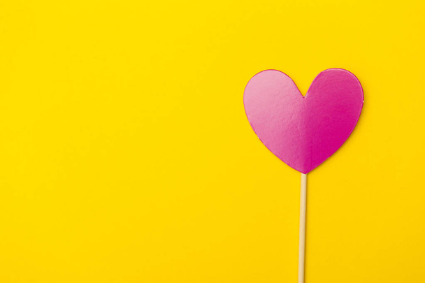Paper heart on a stick over a bright yellow background - Fotografie, Obrázek