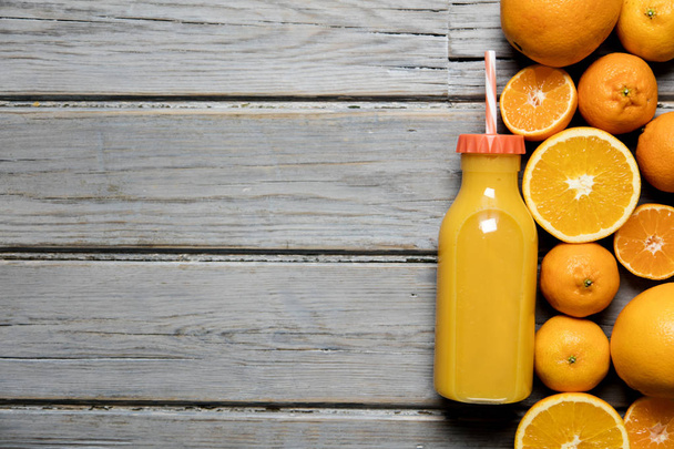 Fresh orange juice in a bottle with oranges on a rustic wooden b - Fotó, kép
