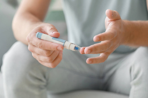 Diabetische man bloedmonster nemen met lancet pen thuis, close-up - Foto, afbeelding