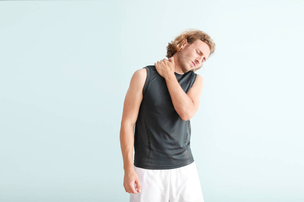junger Mann leidet unter Nackenschmerzen auf farbigem Hintergrund - Foto, Bild
