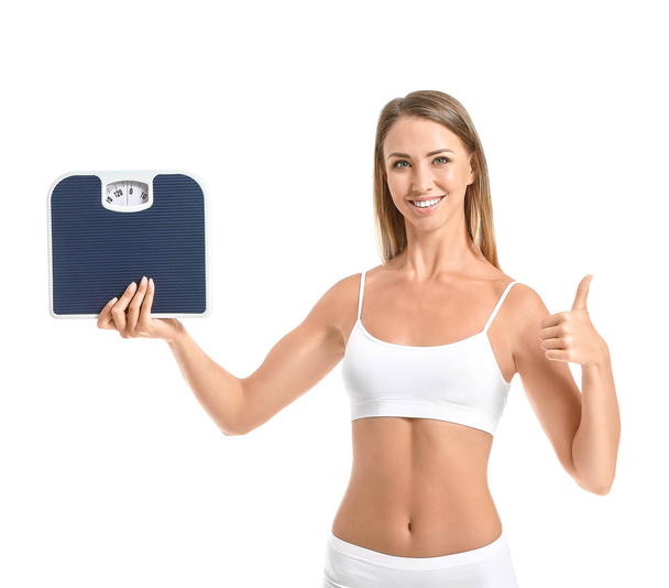 Beautiful young woman with scales showing thumb-up on white background. Weight loss concept - Foto, afbeelding