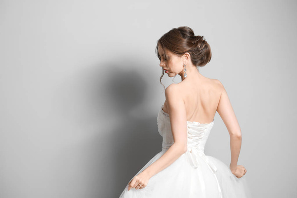 Beautiful young bride on grey background - Фото, изображение