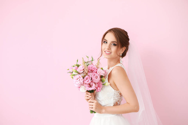Portrait of beautiful young bride with wedding bouquet on color background - Photo, Image