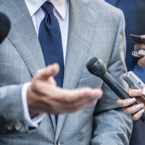 Медіа-інтерв'ю - журналісти з мікрофонами, які інтерв'юють офіційного вдягненого політика або бізнесмена
. - Фото, зображення