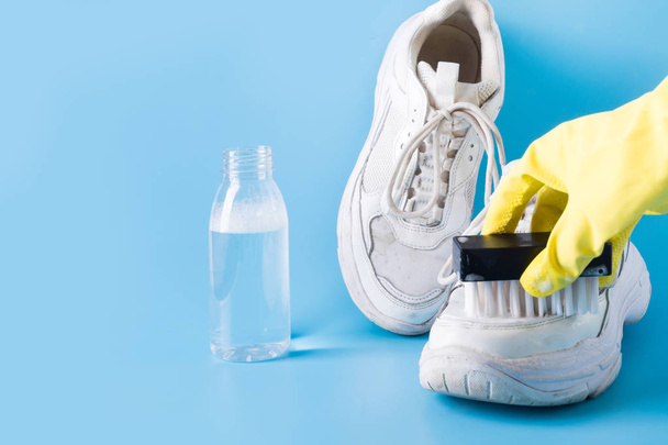 Sneakers bianche sporche con attrezzo speciale per pulirle su blu
. - Foto, immagini