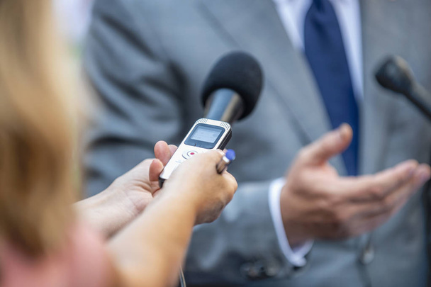 Συνέντευξη Τύπου - δημοσιογράφοι με μικρόφωνα παίρνουν συνέντευξη από επίσημα ντυμένο πολιτικό ή επιχειρηματία. - Φωτογραφία, εικόνα
