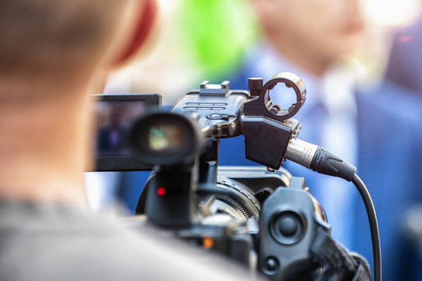 Camera operator working at a press conference outdoors. Journalists interviewing formal dressed politician or businessman at a media event.  - Photo, Image