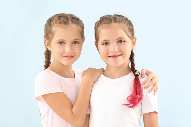 Portret van schattige tweeling meisjes op kleur achtergrond - Foto, afbeelding