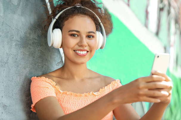 Belo afro-americano com telefone celular ouvindo música ao ar livre
 - Foto, Imagem