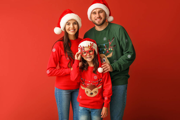Família feliz em camisolas de Natal e chapéus de Papai Noel no fundo de cor
 - Foto, Imagem