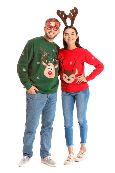 Funny young couple in Christmas sweaters on white background - Foto, Imagen