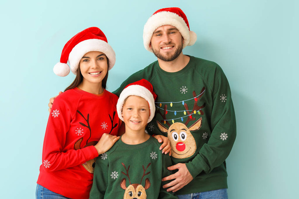 Szczęśliwa rodzina w świąteczne swetry i kapelusze Santa na tle koloru - Zdjęcie, obraz