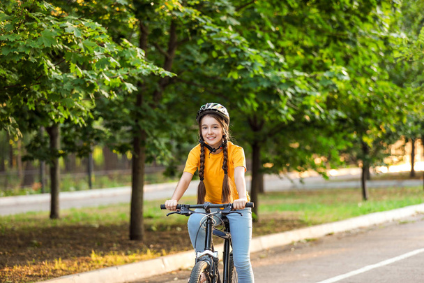 Cute girl riding bicycle outdoors - Photo, image