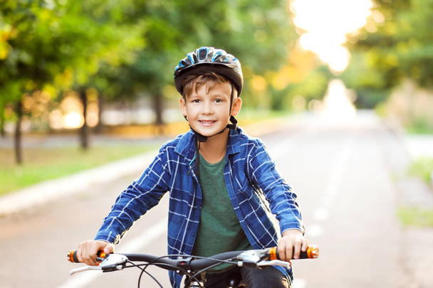 Cute boy riding bicycle outdoors - Фото, изображение