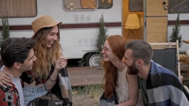 Ryhmä nuoria hymyileviä ystäviä puhuu ja tekee selfie valokuvan älypuhelimella viettäessään aikaa yhdessä lähellä perävaunua
 - Materiaali, video