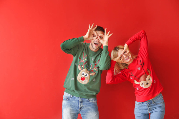 Funny couple in Christmas sweaters on color background - Foto, Imagem