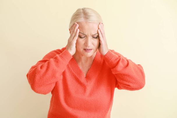Mature woman suffering from headache on light background - Fotó, kép