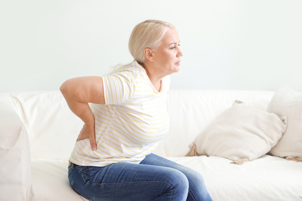 Reife Frau leidet zu Hause unter Rückenschmerzen - Foto, Bild