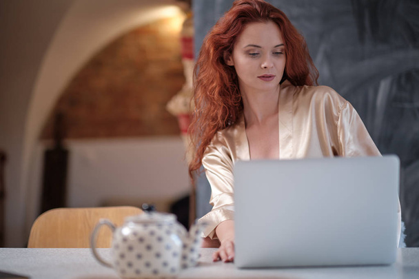 Woman in a bathrobe works on a laptop at home - Photo, Image