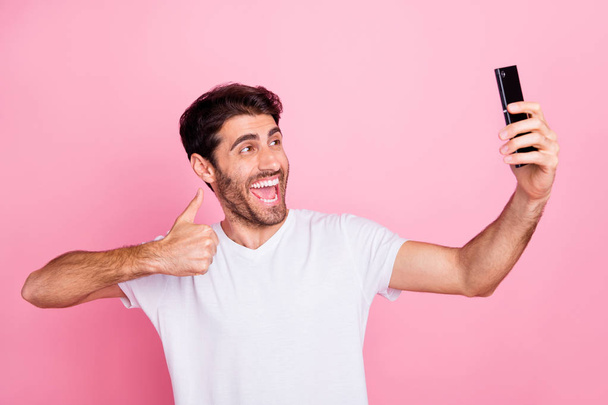Portrait of funny funky crazy cheerful middle eastern man blogger on summer holidays recommend his vacation take selfie show thumb up wear stylish trendy white t-shirt isolated pink color background - Foto, immagini