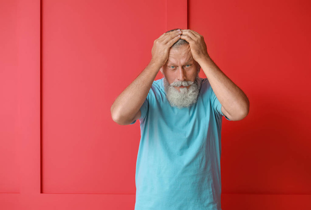 Senior Mann leidet unter Kopfschmerzen auf farbigem Hintergrund - Foto, Bild